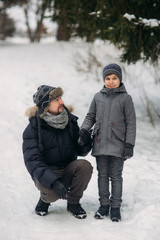 Fototapeta na wymiar Happy father with his son walks through the park in the snowy winter weather