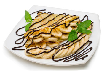Crepes with chocolate cream and banana on white background.