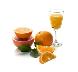 Bodegón de una copa de cristal con zumo de naranja, junto a narajas cortadas sobre un fondo blanco