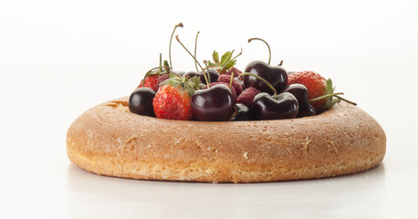 Bizcocho savarín relleno de fresas, frambuesas y cerezass visto frontalmente sobre un fondo blanco 2