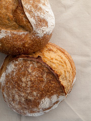 Dos hogazas de pan artesano sobre un mantel de lino vistos cenitalmente