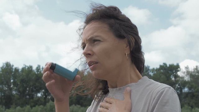 Asthma. Asthma attack. Woman with inhaler on nature.