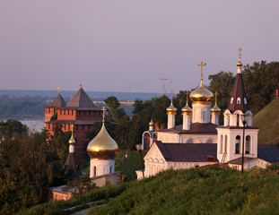 Fototapeta na wymiar Scenic view at St. Elijah's Church, domes of Church of St. John the Baptist and guard towers of of Nizhny Novgorod Kremlin with Volga river in the background at sunset