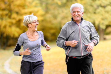 Smiling senior active couple jogging together in the park