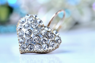 Heart shaped earring decorated with diamonds - elegant reflection - colored background blue - cold color balance