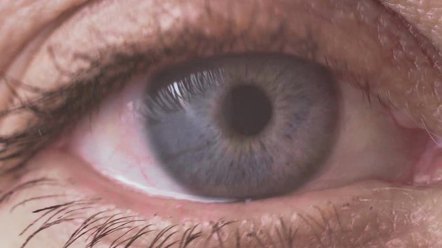 Macro video of the pupil of the female eye of a blond woman at the age of 50