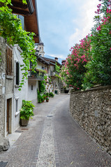 Narrow street with cobblestones and beautiful flowers in Limone, Garda Lake, Italy