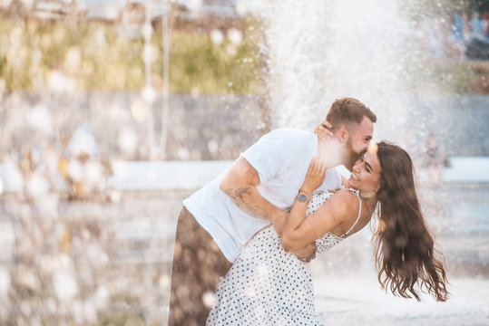Handsome guy and beautiful girls kissing on the background of a fountain