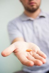 man stretches an orange pill in his palm.Medical.Concept.