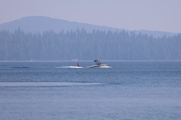 Fototapeta premium Wakeboarding on Cultus Lake, Bend , Oregon. A motor boat pulling a young man on a wakeboard