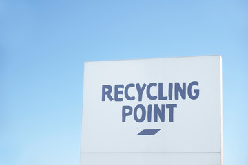 Recycling point direction sign against blue sky
