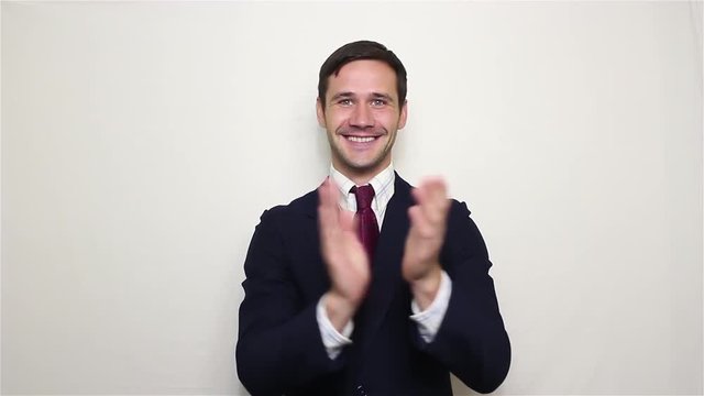 Handsome young businessman smiling and actively clapping hands, greeting new customers.Portrait on a white background.