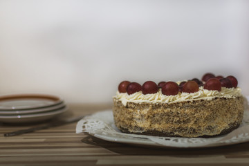 Cream light cake with grape wine on a white tray.