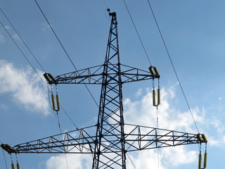 Power line support against blue sky with white clouds. High-voltage electricity transmission line	