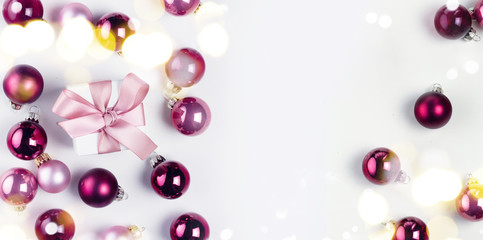 Christmas flat lay scene with pink and violet glass balls and gift box with pink ribon, copy space on white