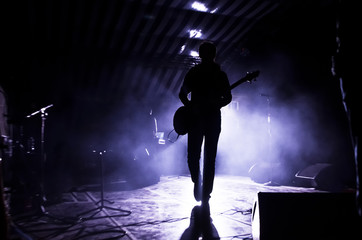 silhouette of a musician, a singer with a guitar on stage in the beams of searchlights. concept of music and rock festival