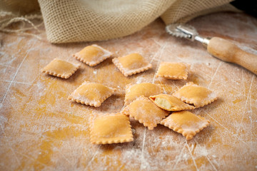 Uncooked rustic style ravioli orange color on a kitchen wooden table