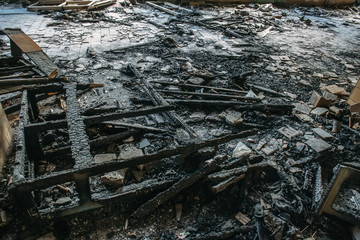 Remains of burnt wooden furniture on the floor of building after fire