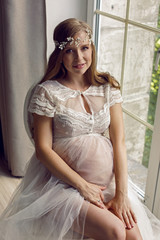 Fototapeta premium pregnant girl in white dress sitting on a chair