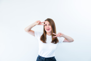 Obraz na płótnie Canvas Portrait of happy girl flirting at camera and showing dancing gesture. Caucasian woman looking through fingers in victory sign isolated on white background. Positive emotion expression. Copy space.