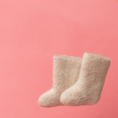 woolen warm winter shoes valenki on a pink background. the concept of winter. winter shoes