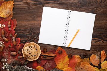 autumn leaves, cookies and paper notebook on wooden background