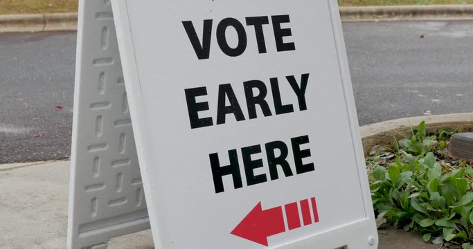 Vote early here sandwich board sign with an arrow pointing to the left