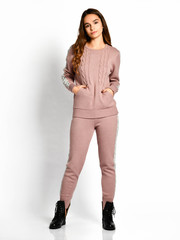 Young beautiful woman posing in new pastel color pink fashion winter knitted suit full body