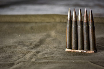 Holder with cartridges 7,92 x 57 - rustic ammos and poncho lies on the wooden background