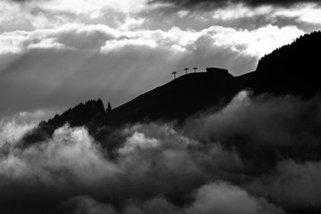 3 Liftstützen am Berghang mit Nebel im Tal
