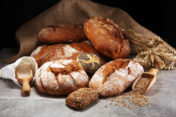 Different kinds of bread and bread rolls on board from above. Kitchen or bakery