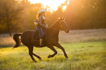 Foto op Canvas Girl equestrian rider riding a beautiful horse © Rakursstudio