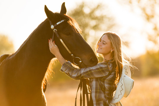 Girl equestrian rider stands near the horse. Horse farm