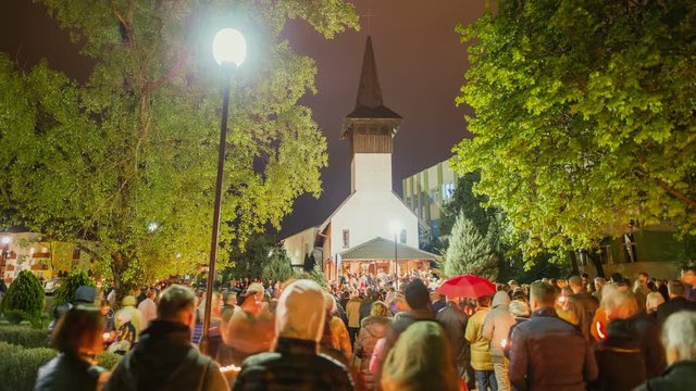 Traditional romanian church surrounded by people with lit candles.
Timisoara city, Romania, cca. 2017