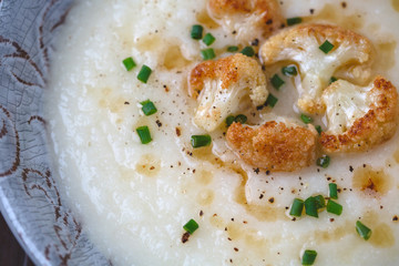 Creamy Cauliflower Soup topped with Brown Butter and Chives in a Rustic Setting