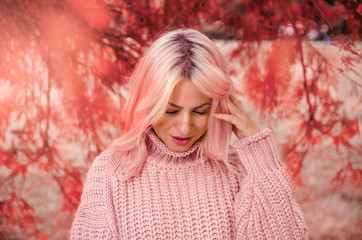 Abstract portrait of beautiful young adult woman in park wearing woolen sweater 