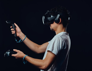 Side view of a man with bristle dressed in white shirt playing games with virtual reality goggles.