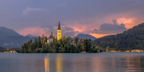 Lake bled with church under lightning stormy sky