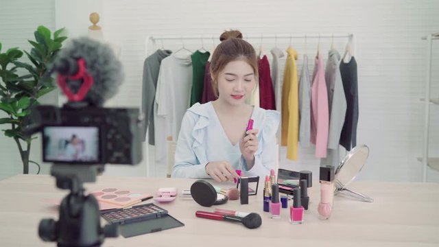 Beauty blogger present beauty cosmetics in front camera for recording video. Beautiful asian woman use cosmetics while review make up tutorial broadcast live video to social network by internet.