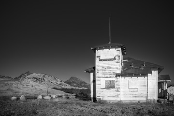 Scary old abandoned schoolhouse with hills and sky black and white hills and sky black and white