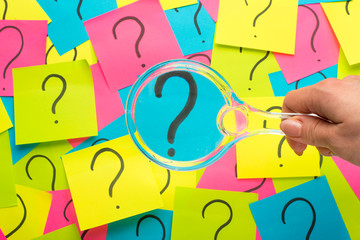 Concept with question mark on sticky note and magnifying glass