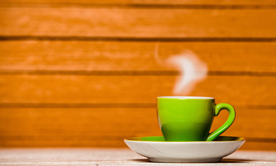 green cup of coffee or tea with steam on wooden background