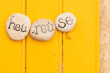 Inscription heureuse sur des galets, fond en bois jaune