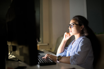 Side view portrait businesswoman working at computer late at night in dark office, copy space