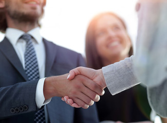 Businesspeople  shaking hands against room with large window loo