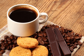 Cup of coffee, cookies and chocolate bars on wooden background