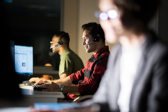 Row of customer service operators working at night in dark office
