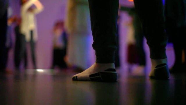 Low angle of woman feet in sock dancing - Filmed from the ground, at night, in a round room with colored lights