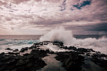 Old classic style lighthouse on the coast of the ocean with wind and clouds in movement. Waves and wild place to enjoy the travel. Wanderlust concept