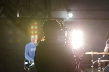 Professional videographer using cinema digital video camera for filming a music video.